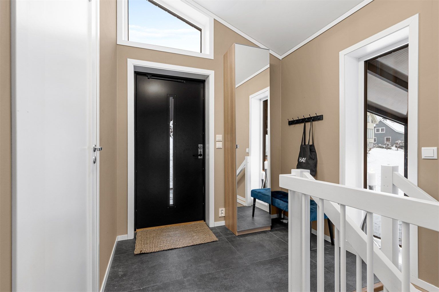 Entré med flislagt gulv og plass til oppbevaring. Fra entreen kommer man videre til gangen og har tilgang til trappen ned til underetasjen.