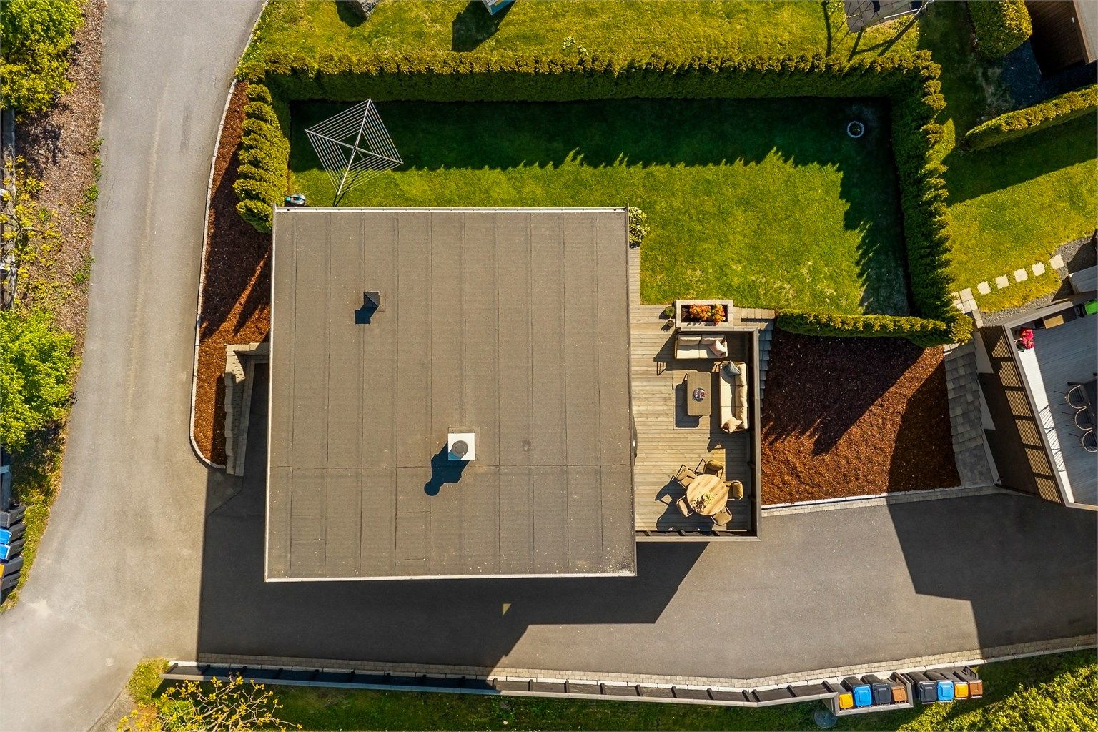 Tomten er effektivt utnyttet med asfaltert gårdsplass, hage og stor terrasse.