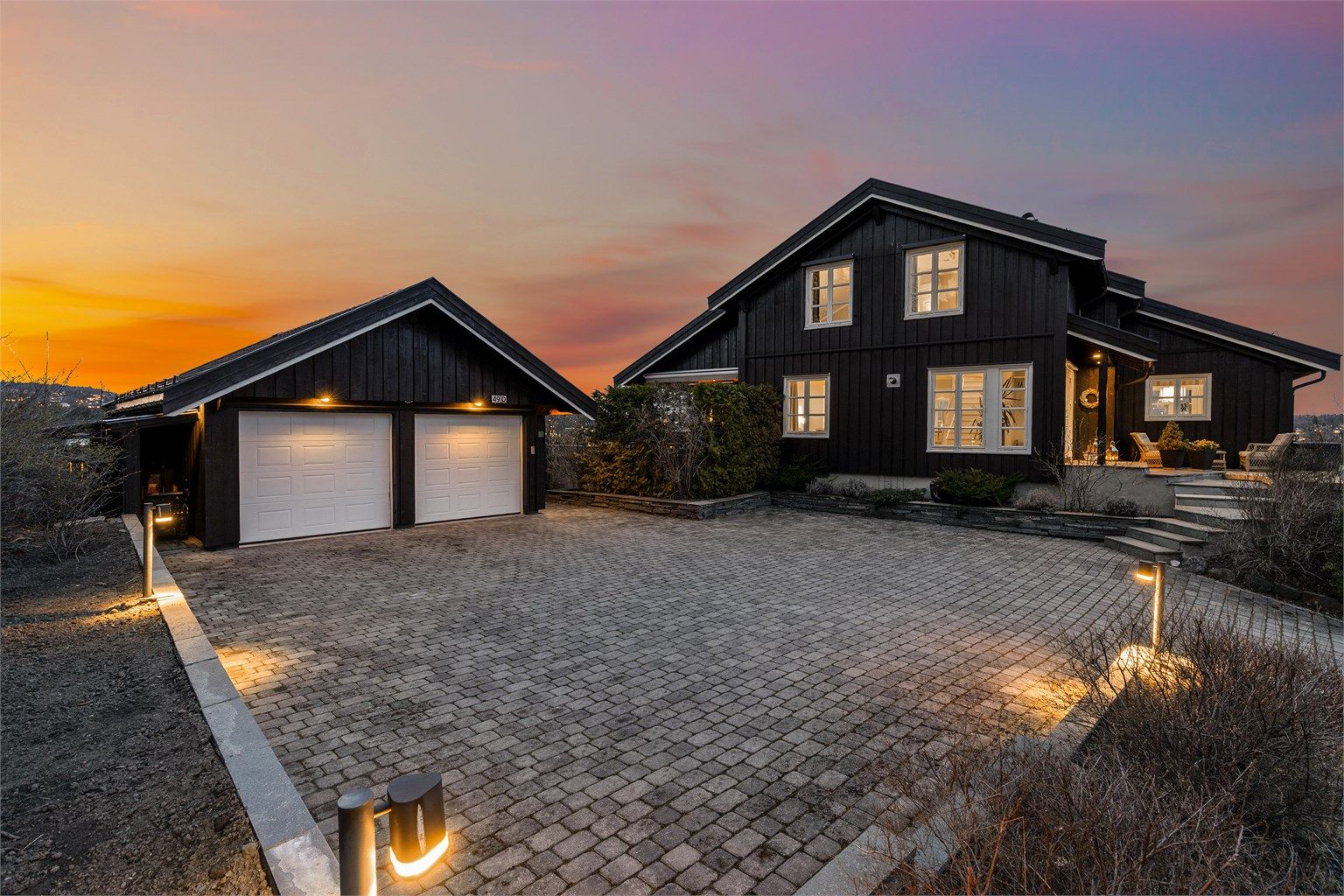 Boligen har en flott, steinlagt gårdsplass med dobbelgarasje. Det er i tillegg en annen garasje på eiendommen. Foto: Trond Reder