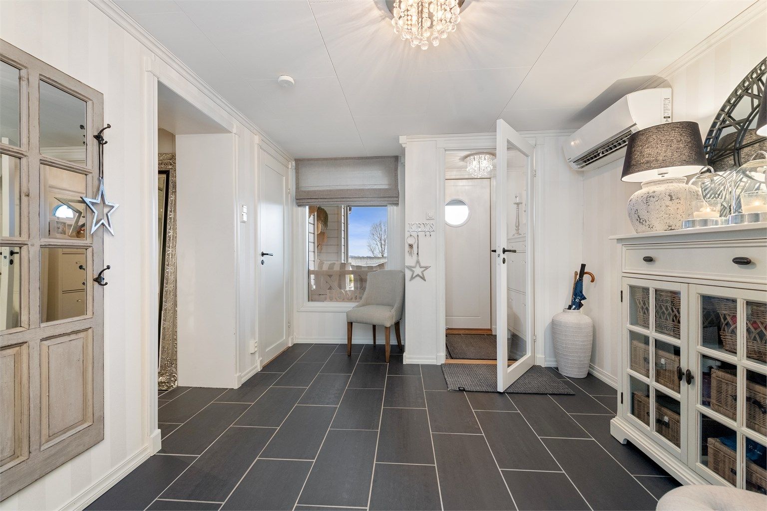 Den romslige hallen i underetasjen har flislagt gulv med gulvvarme