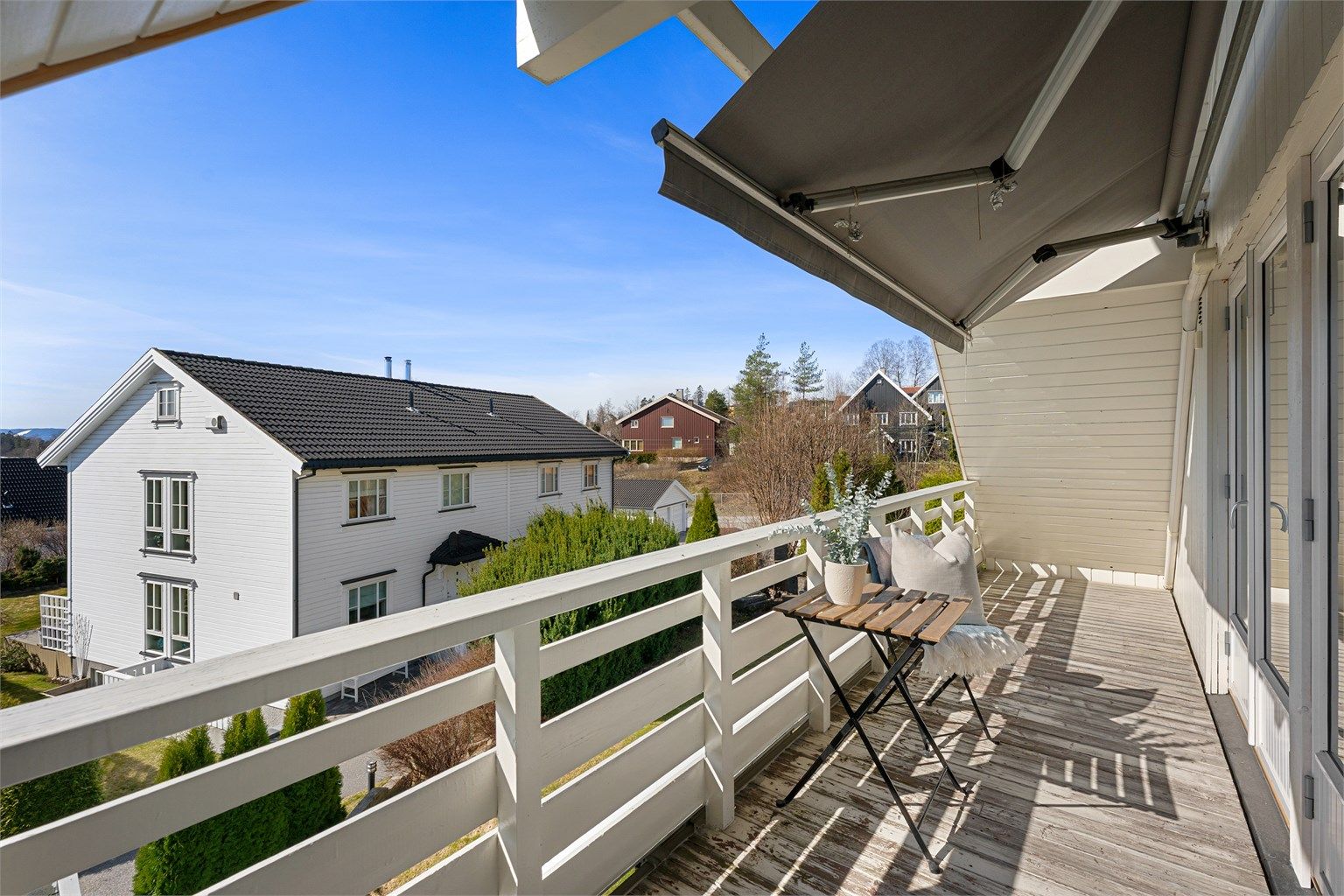 Balkongen er belagt med terrassebord og har plass til en liten sittegruppe.