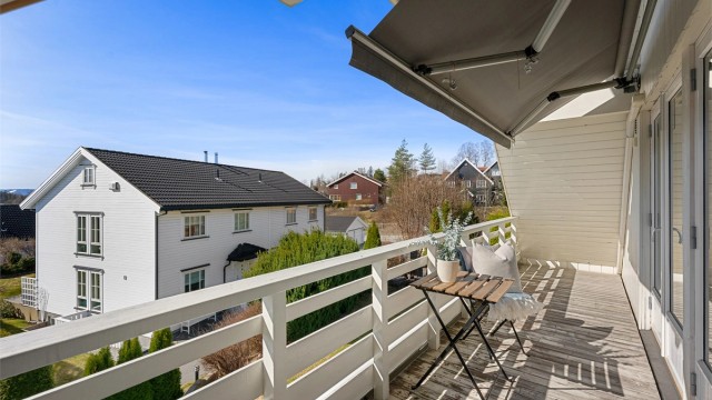 Balkongen er belagt med terrassebord og har plass til en liten sittegruppe.