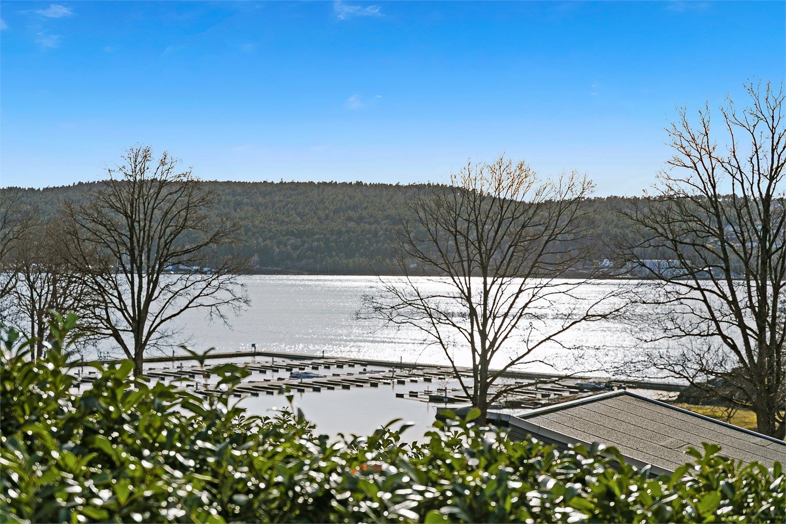 Fra hytta og uteplassen er det utsikt ned til en liten vik med brygger og badeplass.
