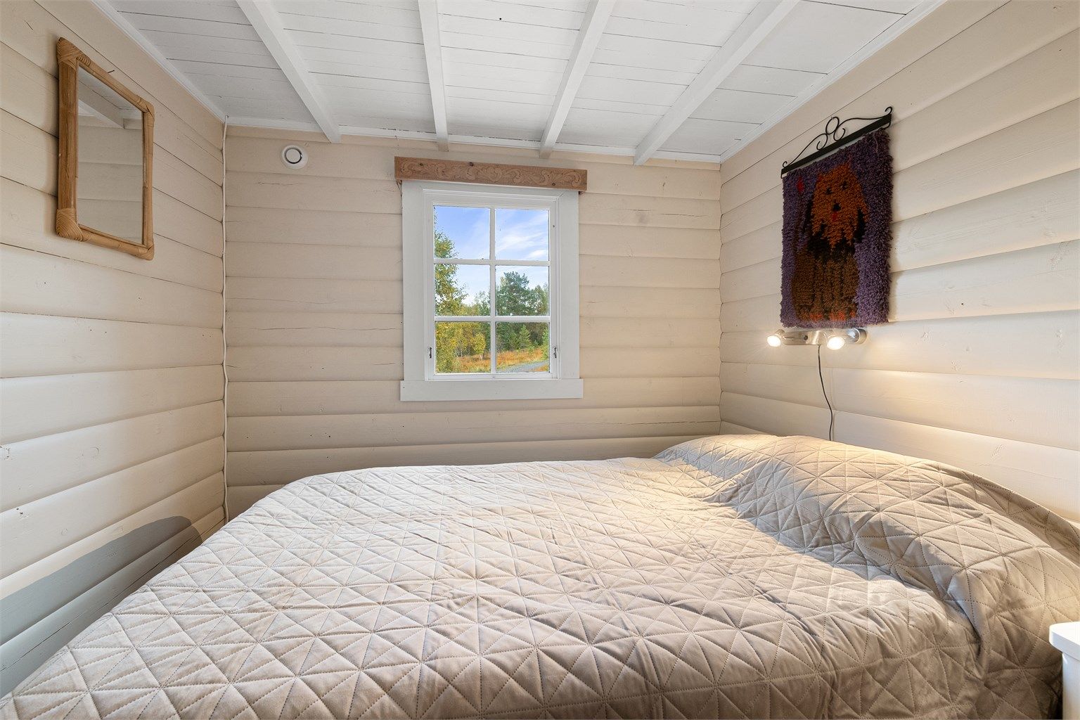 Soverom med heltre gulv og malt panel på vegger og i himling.