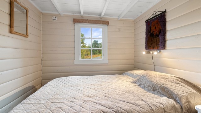 Soverom med heltre gulv og malt panel på vegger og i himling.