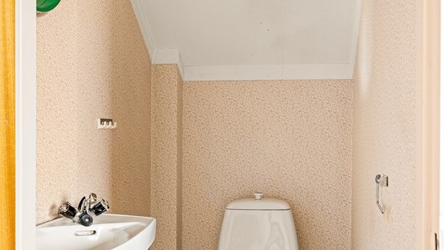 Toalettrom i andre etasje med servant, toalett og panelovn for oppvarming.
