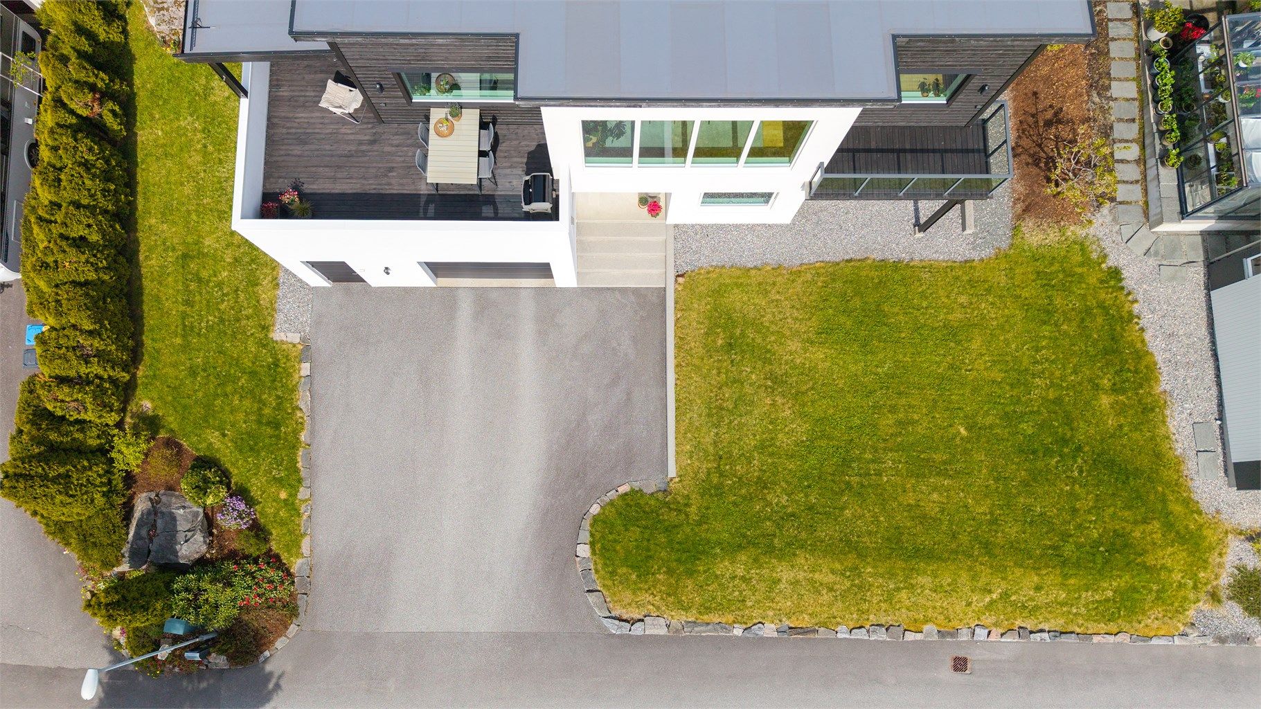 Tomten er pent opparbeidet med asfaltert gårdsplass, plen og beplantning