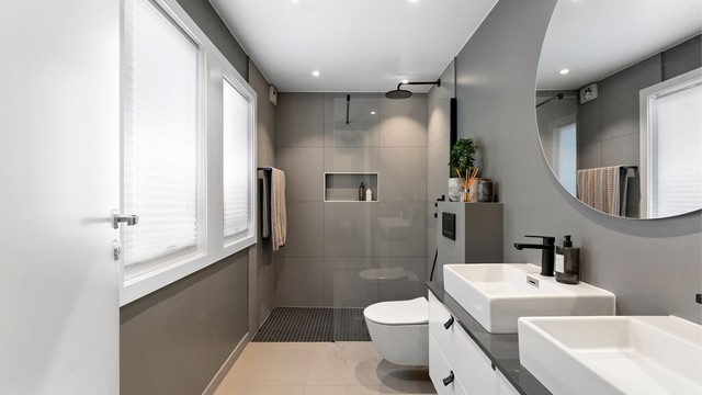 Lekkert bad fra 2018 med fliser på gulv og på vegger. Badet har servantinnredning med doble vasker, vegghengt toalett og dusj med glassvegg. Det er malt himling med downlights