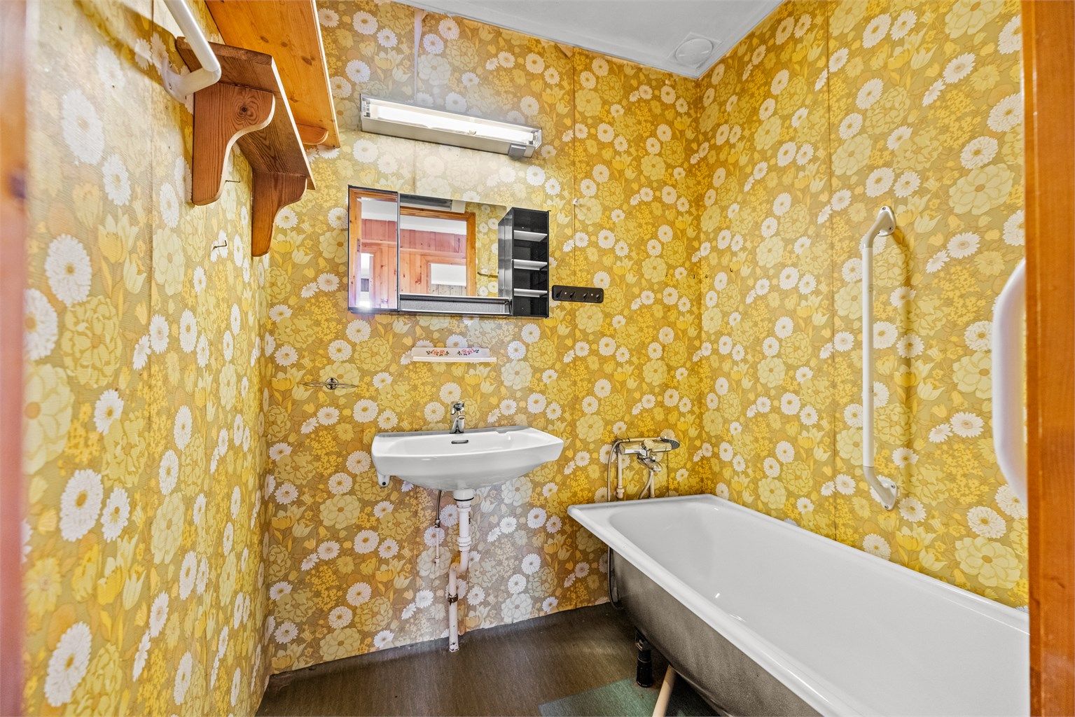 Badet er av eldre dato og utstyrt med badekar og servant.