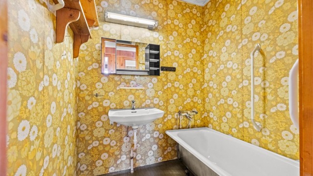 Badet er av eldre dato og utstyrt med badekar og servant.