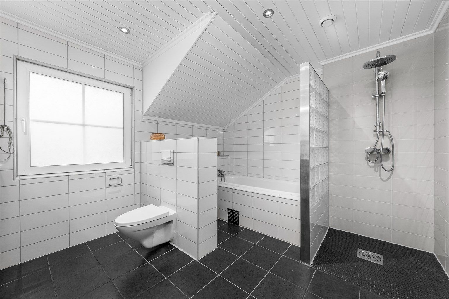 Pent, flislagt bad med varmekabler i gulvet, utstyrt med både dusjhjørne og badekar.