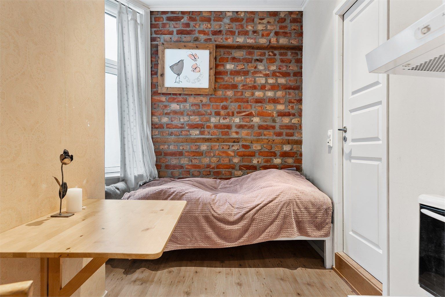 I hybeldelen er det plass til et lite spisebord samt sofa/seng i enden av rommet. Døren til høyre går inn til badet i hybelen.