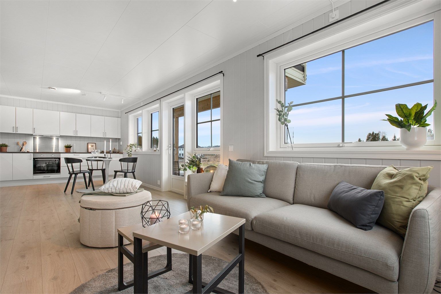 Stue og kjøkken i lyse farger og godt med vinduer som gir innslipp av dagslys