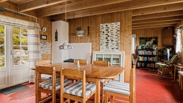 Fra spisestua er det utgang til uteplassen bak hytta. I hjørnet bak spisebordet er det en liten vedovn.