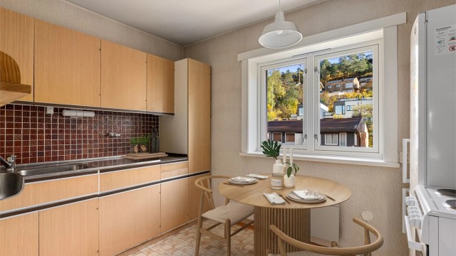 Kjøkken med spiseplass ved vinduet og innredning med finérfronter.