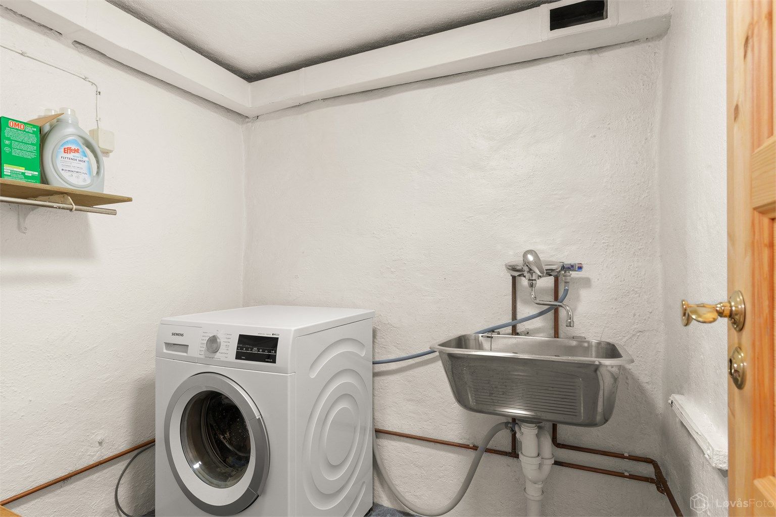 Separat vaskerom i kjelleren med flislagt gulv og opplegg for vaskemaskin.