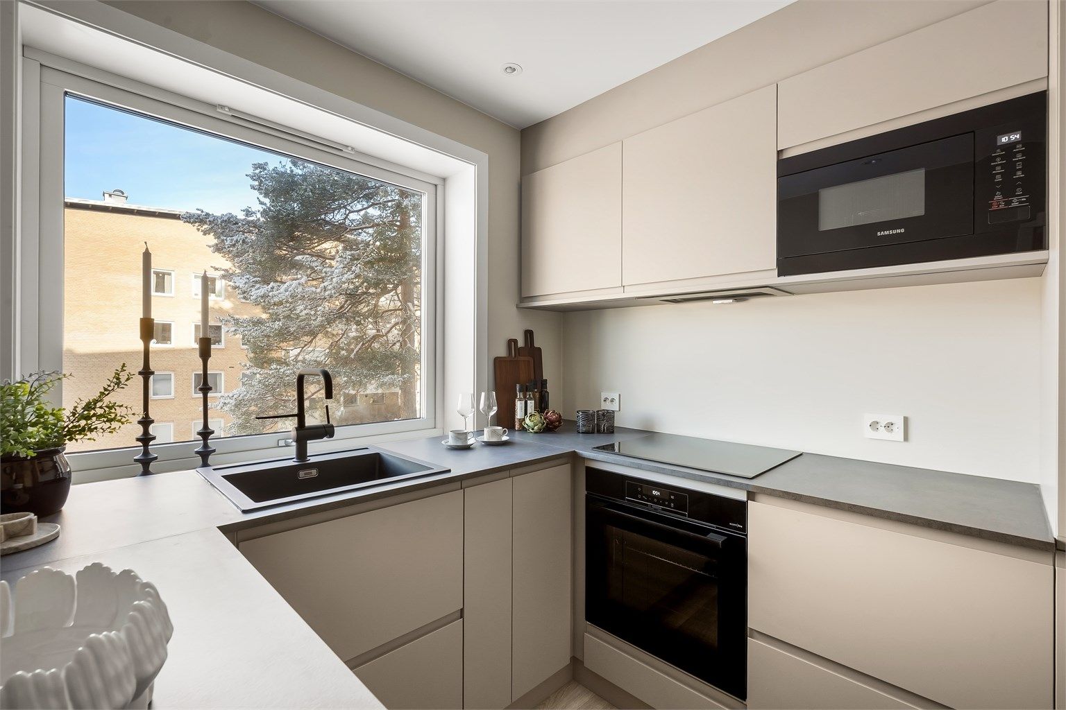 Kjøkkenet er utstyrt med integrerte hvitevarer fra kjente merket, inkludert induksjonstopp og mikroovn.