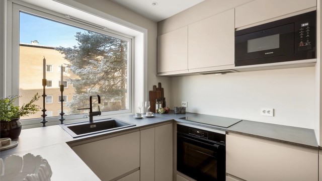 Kjøkkenet er utstyrt med integrerte hvitevarer fra kjente merket, inkludert induksjonstopp og mikroovn.