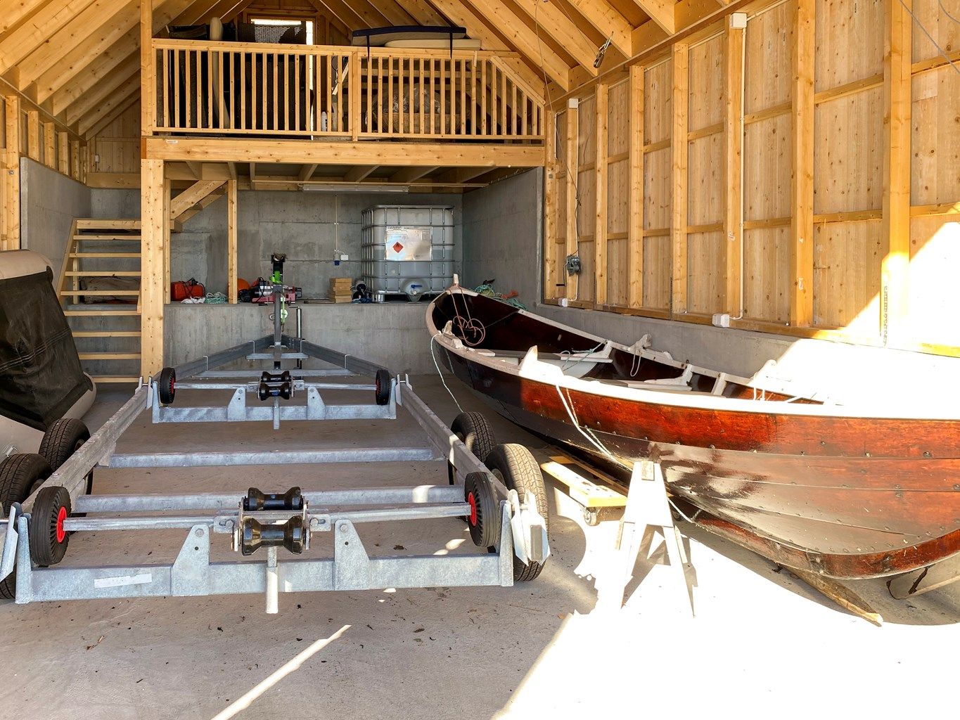 Naust innvendig med god takhøyde og messaninetasje i bakkant. Det er inngang fra nord