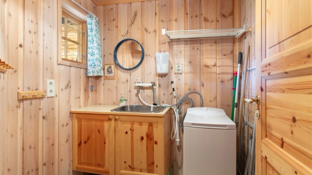 Praktisk vaskerom med flislagt gulv, varmekabler og opplegg for vaskemaskin.