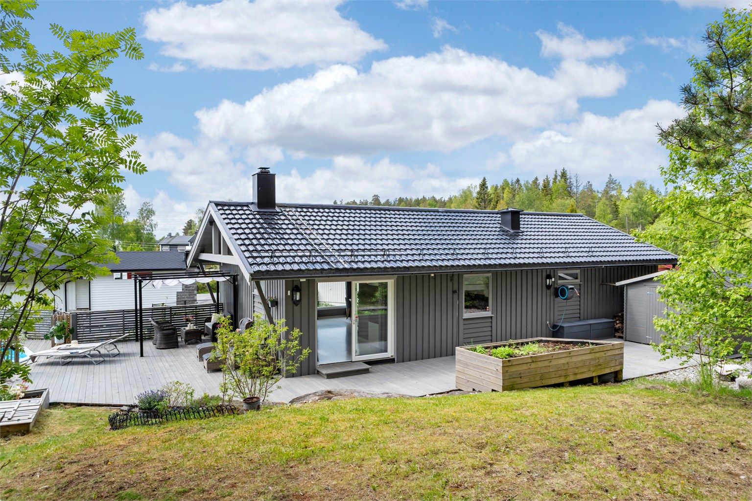 Baksiden av huset med utgang fra stuen til en markterrasse.