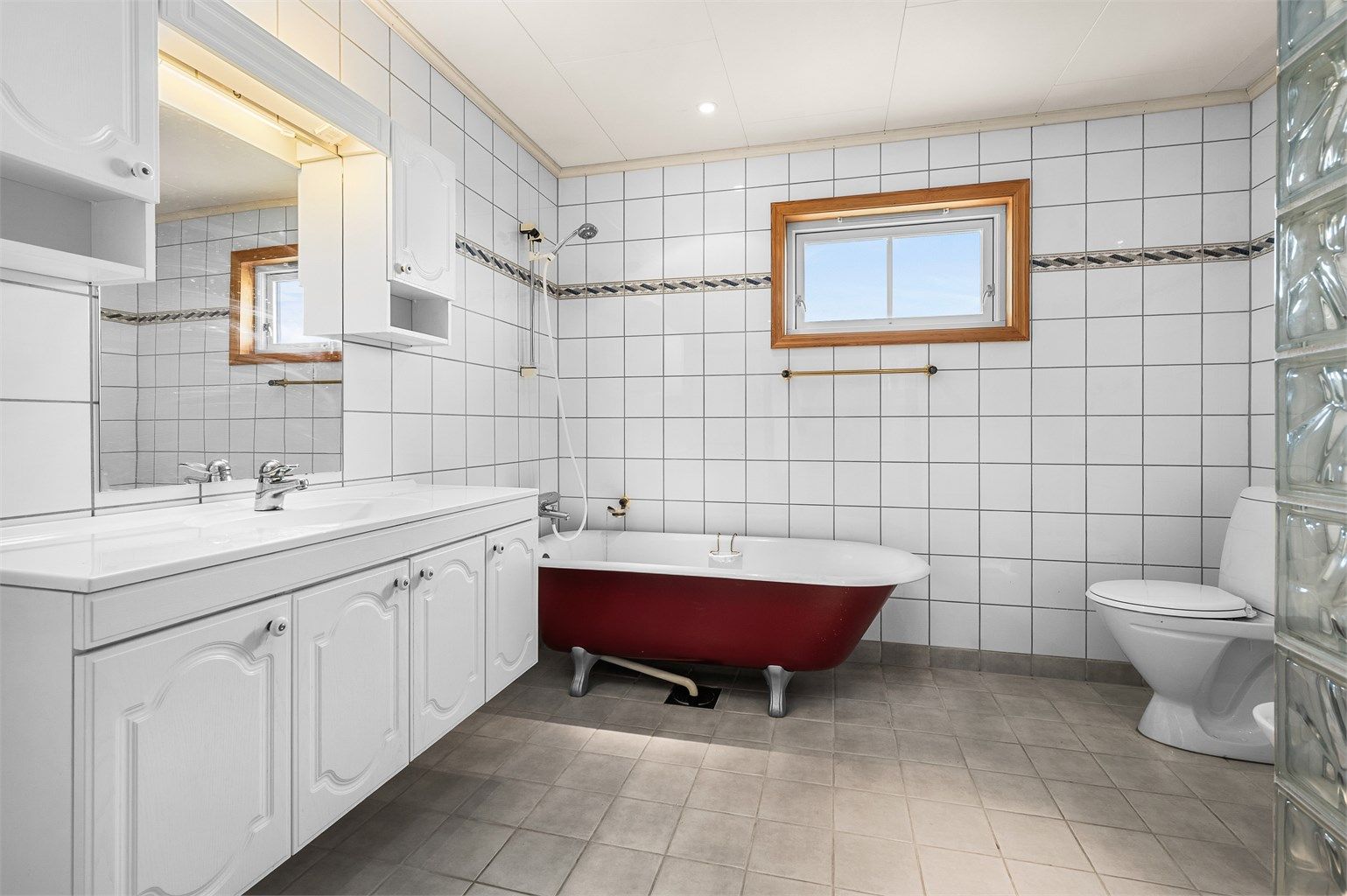 Romslig bad med flislagte overflater, godt med skapplass og en klassisk innredning med badekar som gir rommet særpreg.