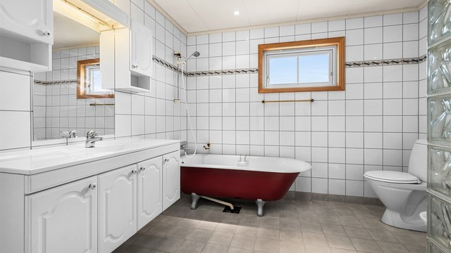 Romslig bad med flislagte overflater, godt med skapplass og en klassisk innredning med badekar som gir rommet særpreg.