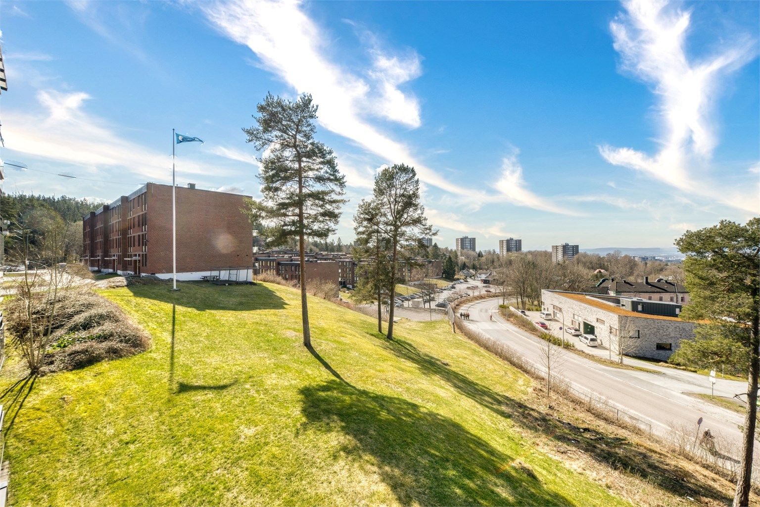 Utsikt fra balkongen mot grønne og rolige fellesområder.
