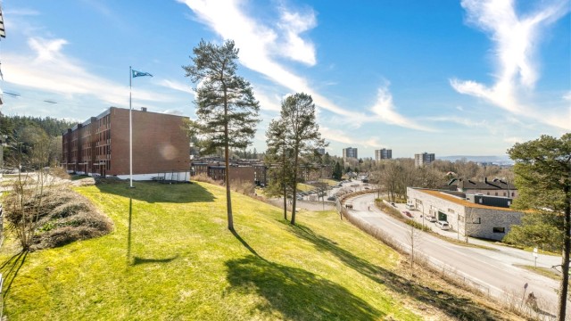 Utsikt fra balkongen mot grønne og rolige fellesområder.