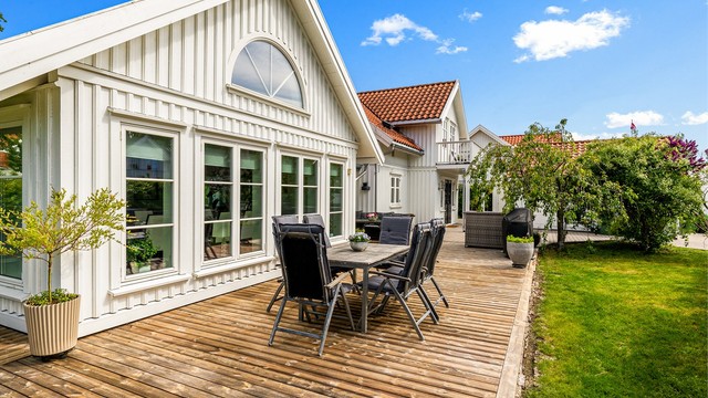 Lettstelt hage med store terrasse flater, gressplen og noe beplanting.