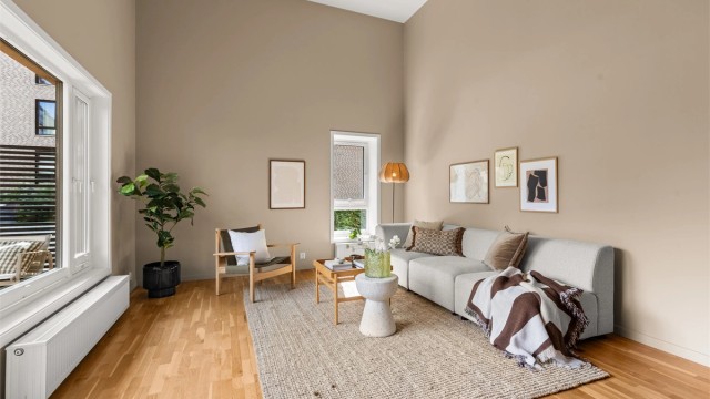 Den åpne stuen byr på god plass til både sofagruppe og spisebord, med utsyn mot en skjermet, grønn bakgård.