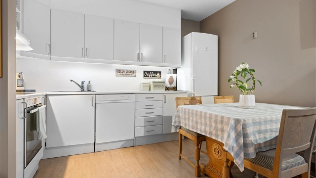 Kjøkkeninnredning med hvite slette fronter og laminert benkeplate. Benkeskapsbelysning og stikkontakter under overskap