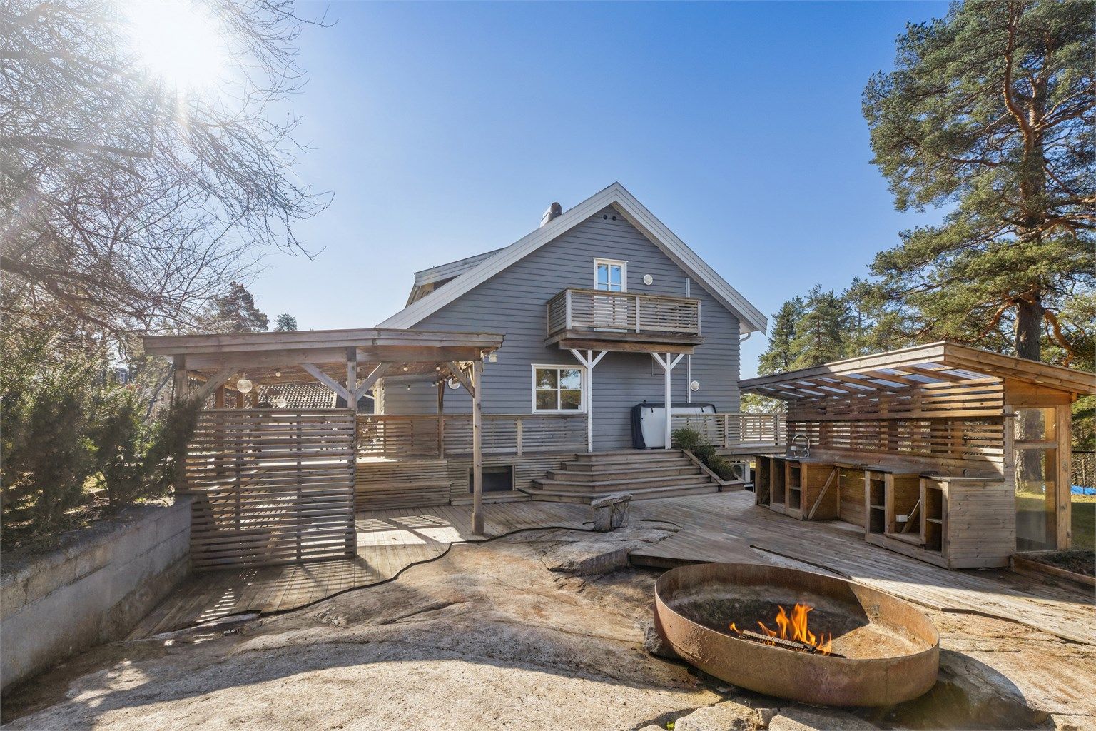 På nordsiden av boligen finner du et flott uteområde som er pent opparbeidet med pergola, fullt utstyrt kjøkken samt en hyggelig bålplass.