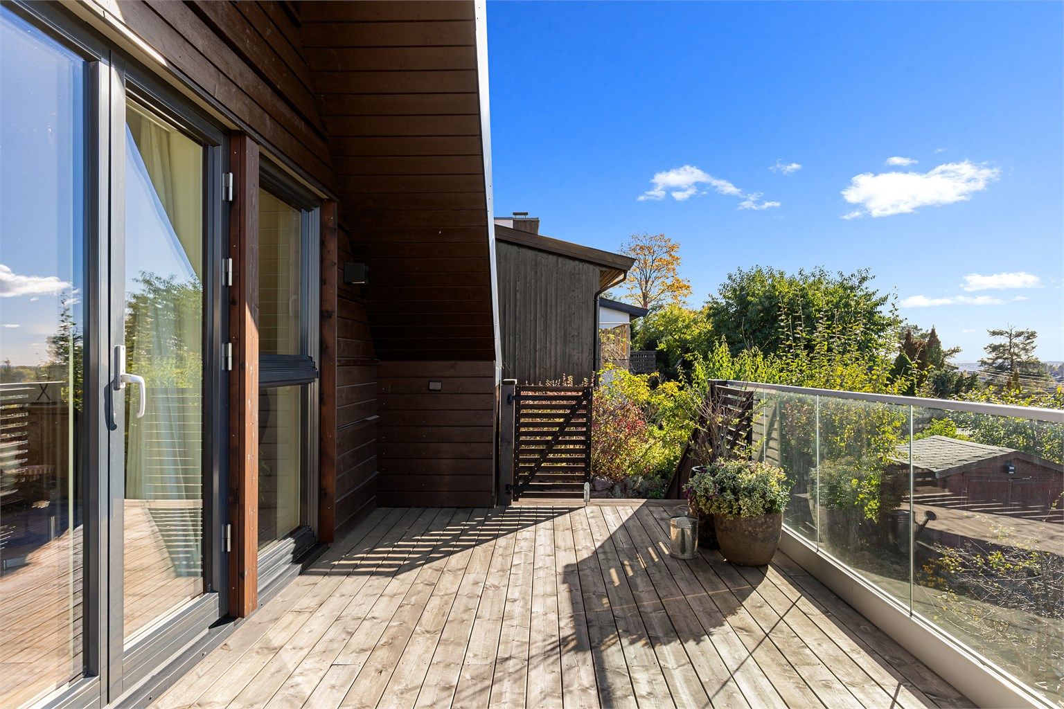Balkongen har gulvflate belagt med terrassebord og rekkverk med glassfelt.
