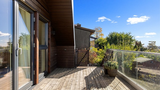 Balkongen har gulvflate belagt med terrassebord og rekkverk med glassfelt.