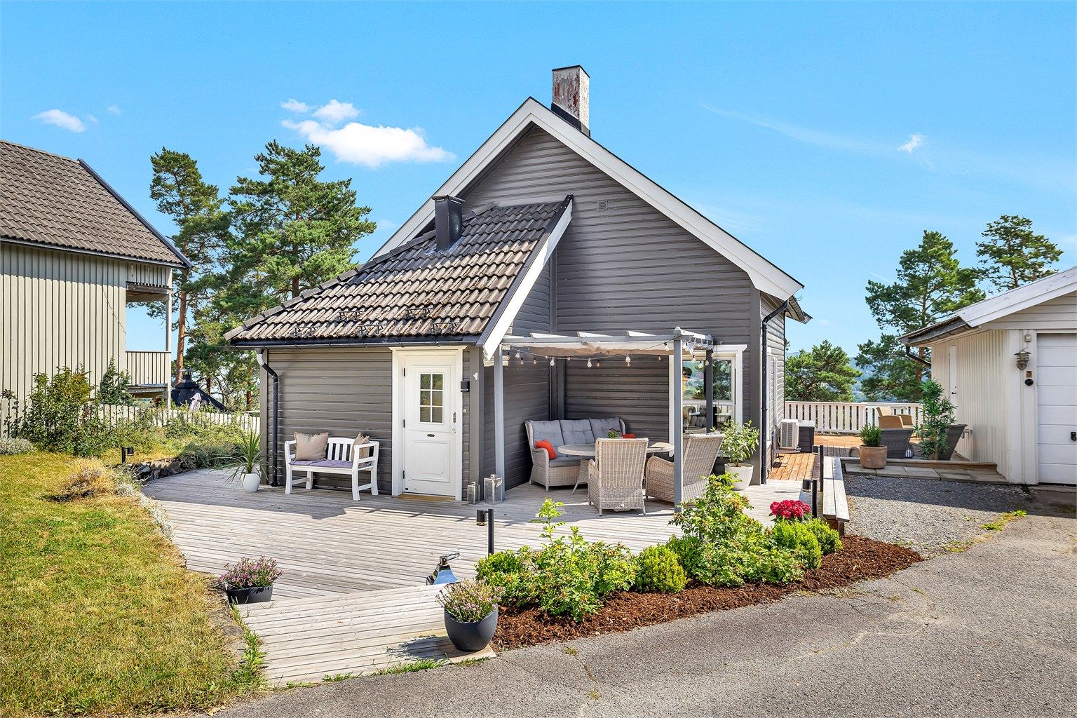 Boligen har et pent inngangsparti med stor platting som binder flere av boligens uteplasser sammen.