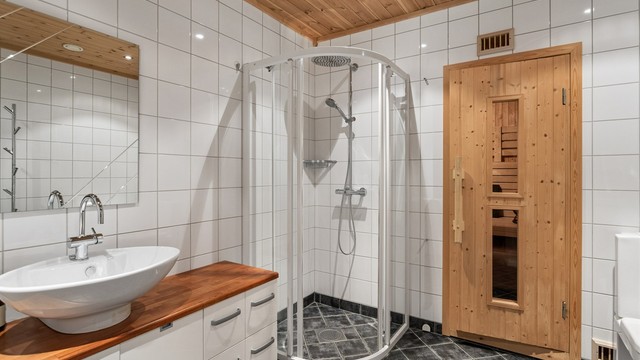 Dusjhjørne med buede glassdører, hånddusj og takmontert regndusj.