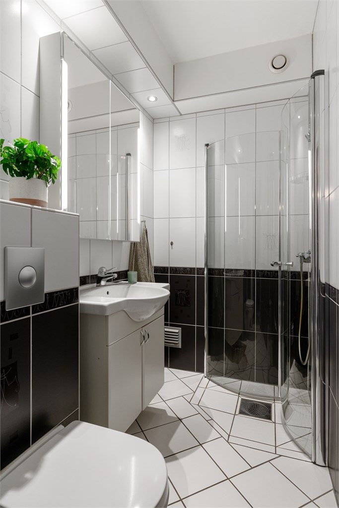 Videre har badet vegghengt klosett og et dusjhjørne med svingbare glassdører.