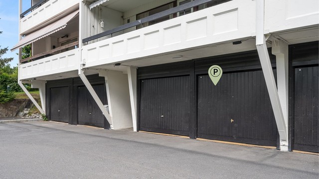 Garasje med elbil-lader ved blokkens inngangspartier - forøvrig god plass til gjesteparkering på sameiets tomt