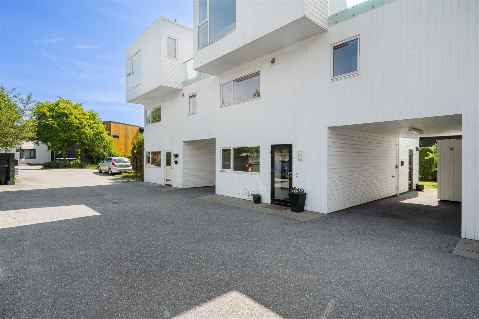 Romslig carport med el-billader. Praktisk biinngang fra carport.