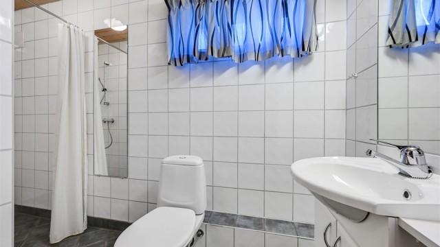 Lyst og praktisk baderom med flislagte overflater og god plass rundt både dusj og innredning.