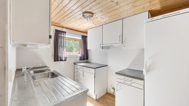 Kjøkkenet i underetasjen har en enkel innredning med laminatbenkeplate og oppvaskkum i stål.