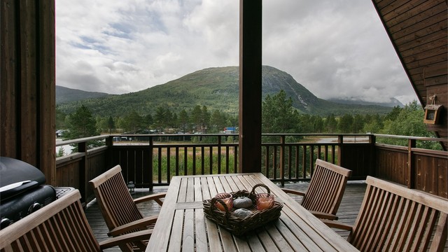 Plass til spisebord ute på balkongen med utsikt mot de omkringliggende fjellene.
