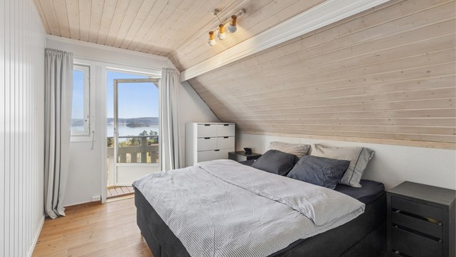 Hovedsoverommet har god plass til en stor dobbeltseng med tilhørende nattbord. Herfra er det utgang til en usjenert, nordøstvendt veranda på ca. 6 kvm med vakker sjøutsikt