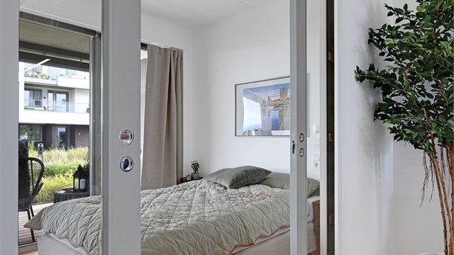 Kontor/tv-stue med tofløyede glassdører som åpner mot stuen