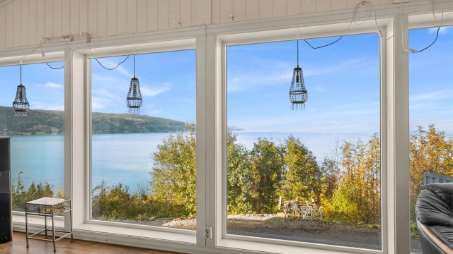 Store glassflater gir et åpent utsyn mot fjorden og landskapet utenfor.