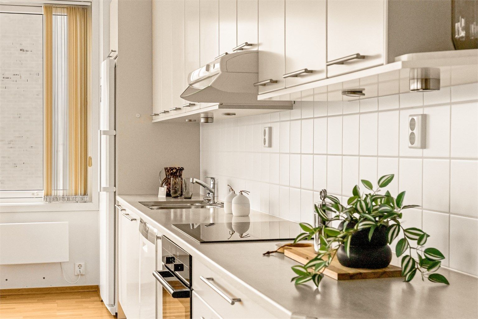 Laminert benkeplate med nedsenket platetopp og hvite fliser på vegg over benken.