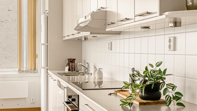 Laminert benkeplate med nedsenket platetopp og hvite fliser på vegg over benken.