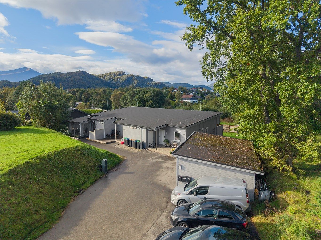 Dronebilde av fasade og felles carport og parkeringsplasser