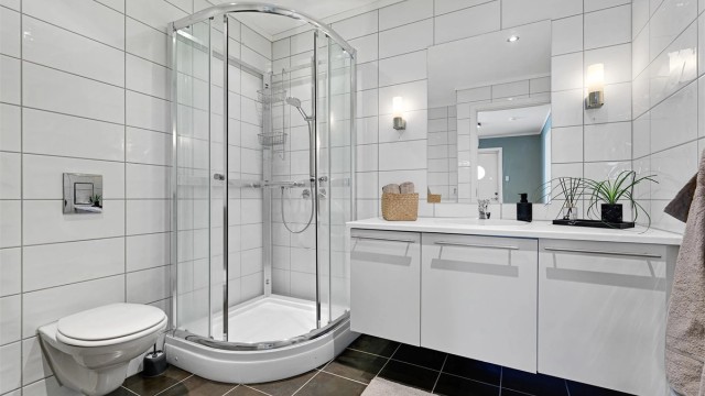 Badet er flislagt og utstyrt med toalett, servant i baderomsinnredning, dusjkabinett og opplegg for vaskemaskin.